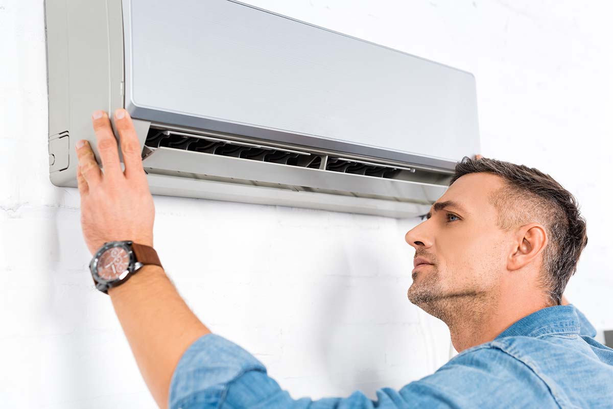 handsome adult man looking into air conditioner