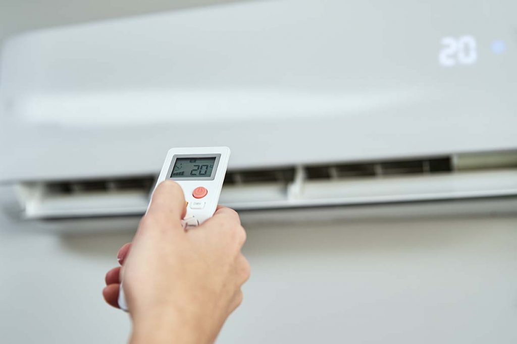 Hand adjusting temperature on air conditioner